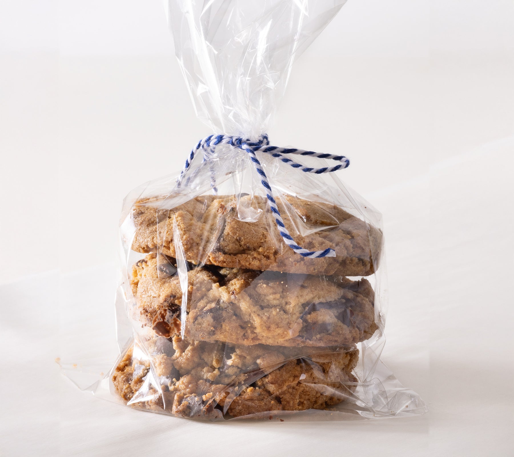 Clear plastic bag with blue string holding cookies on a white background