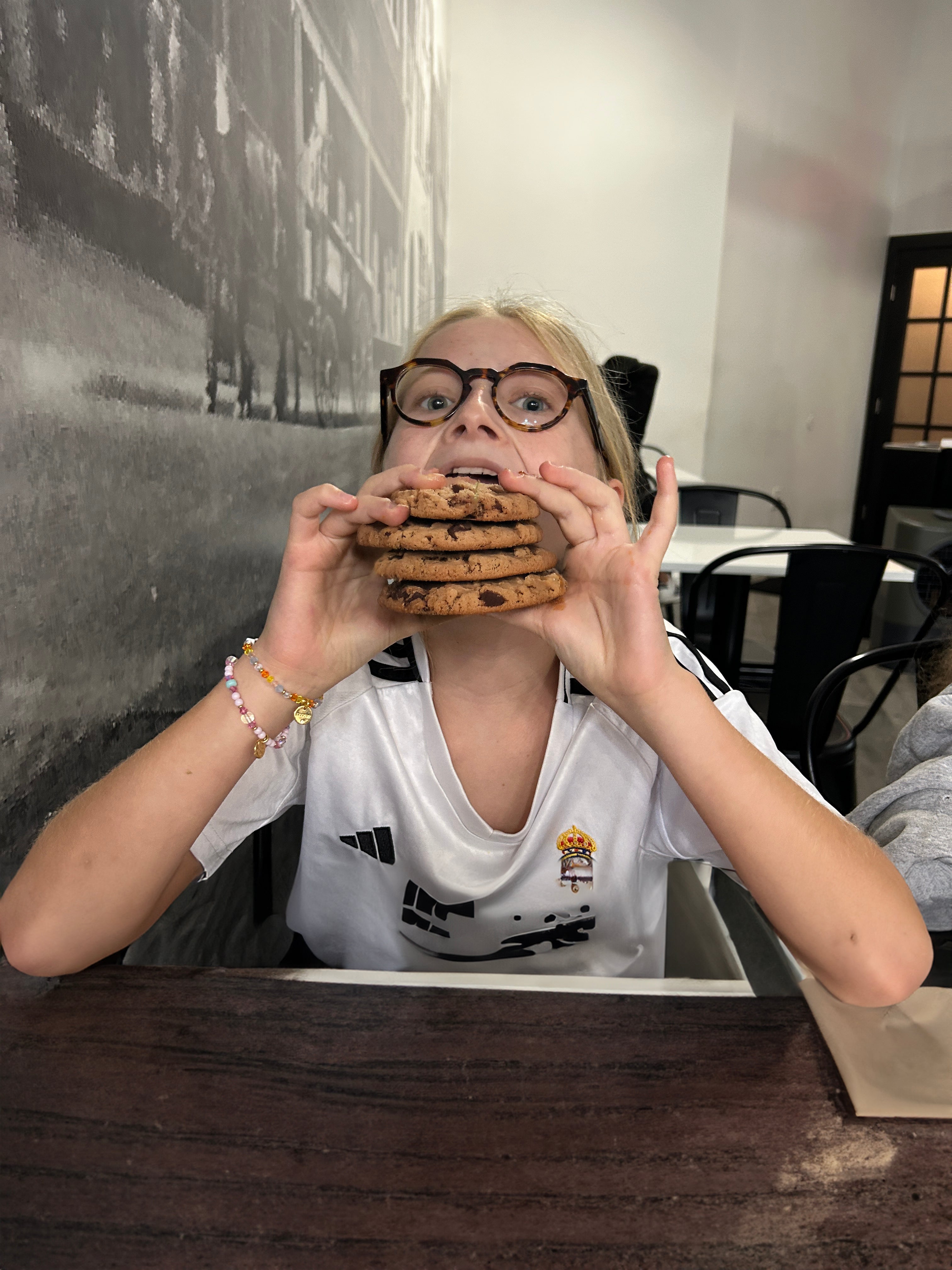 Girl holding a stack of cookies in front of their face in an indoor setting