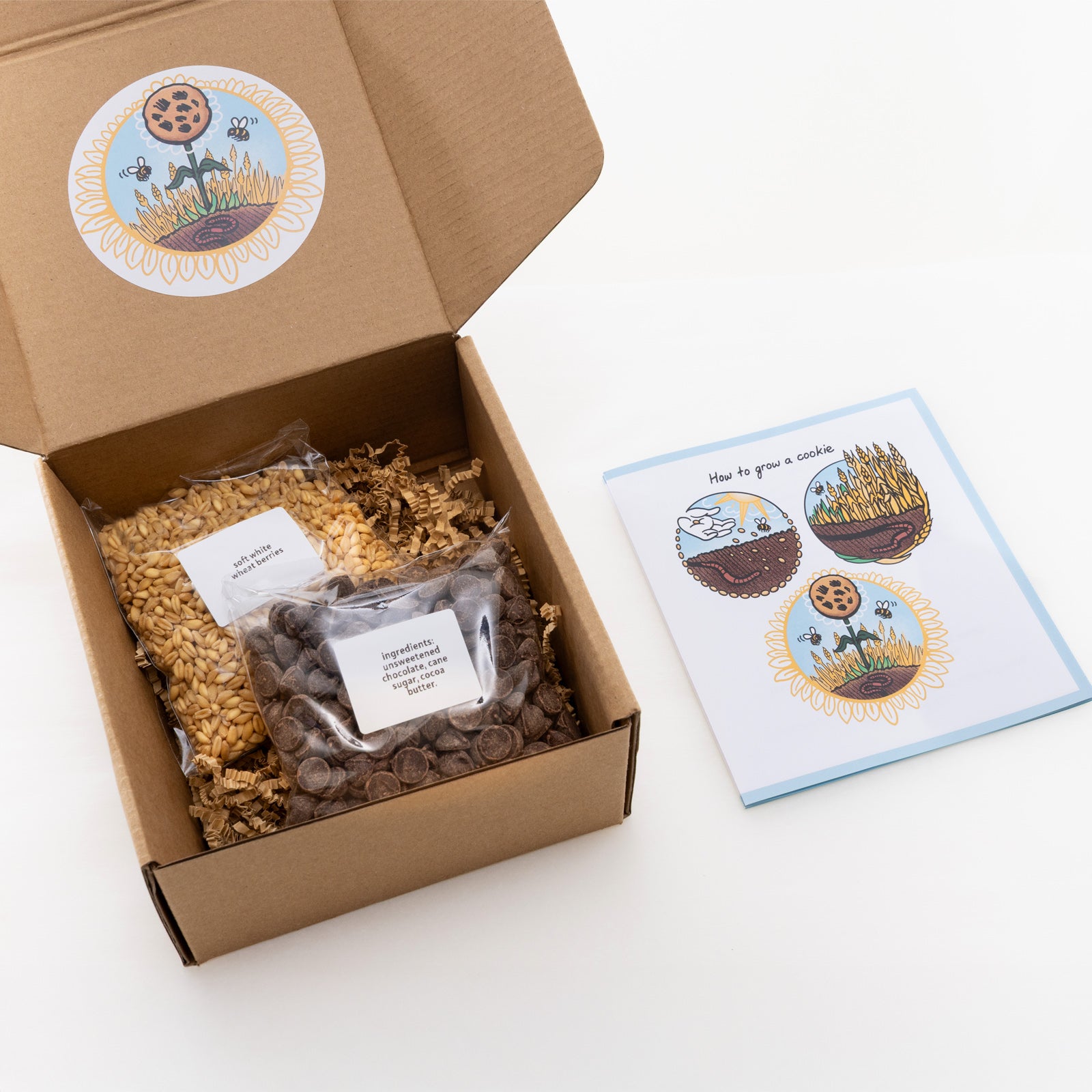 Open cardboard box containing ingredients for cookies with a recipe card on a white background