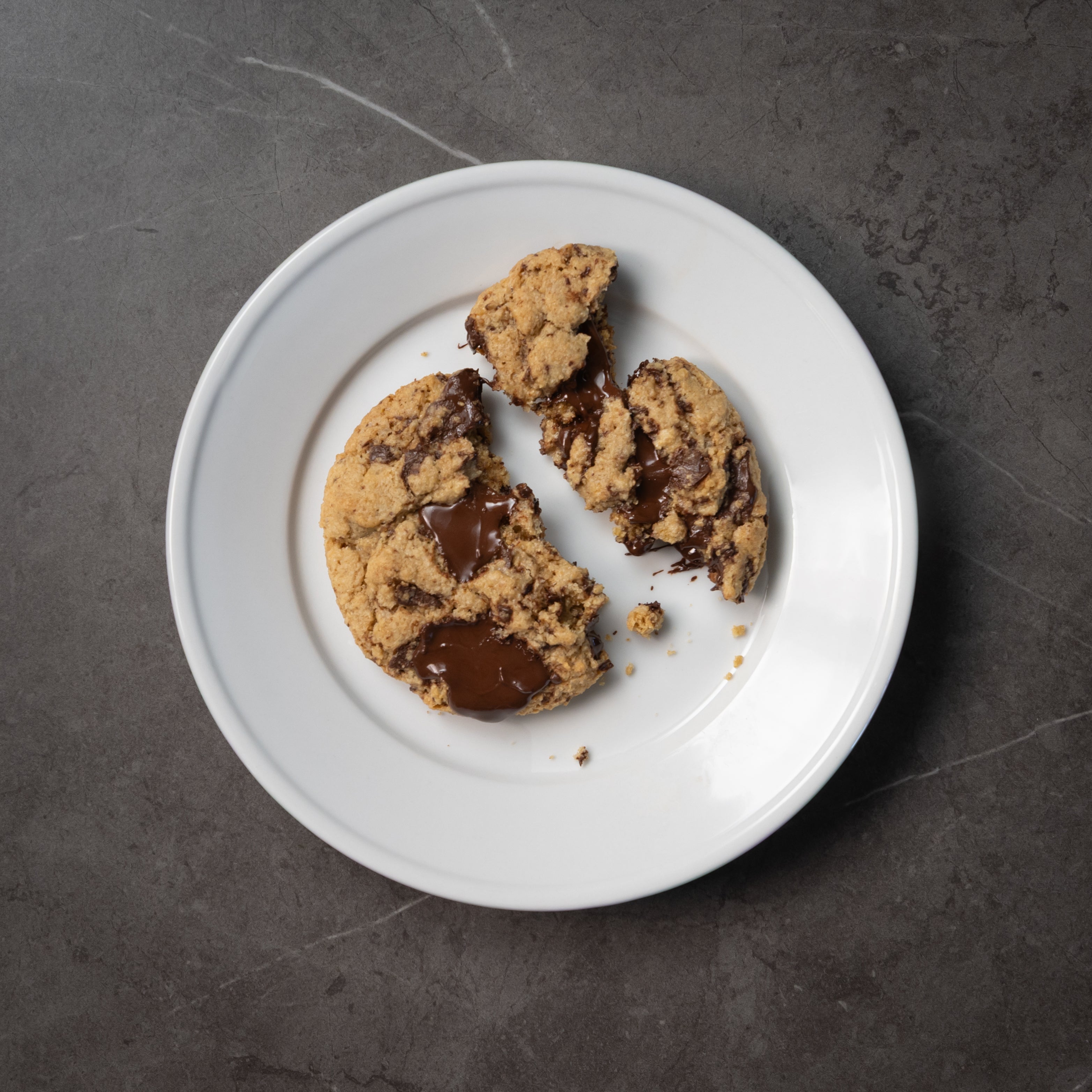 Chocolate chip cookies on a white plate with a dark background