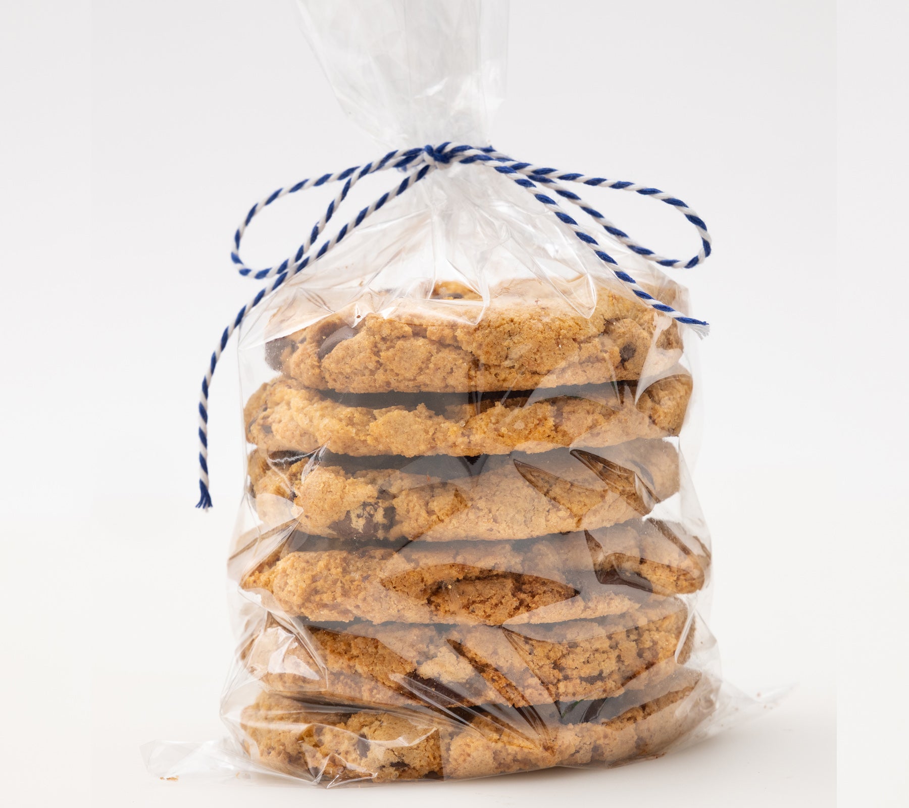 Clear plastic bag filled with cookies tied with blue string on a white background